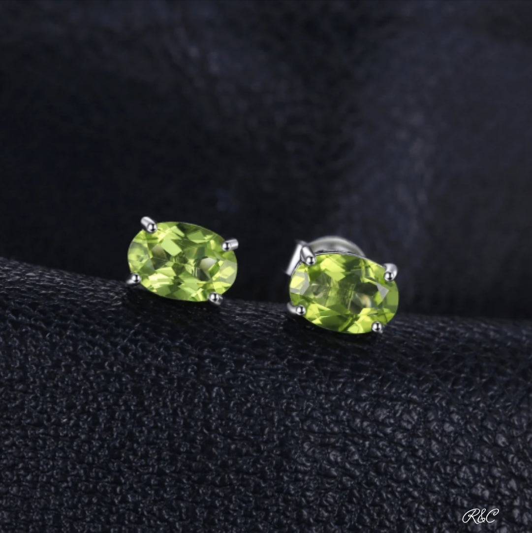 Natural Peridot oval green gemstone sterling silver stud earrings on black background
