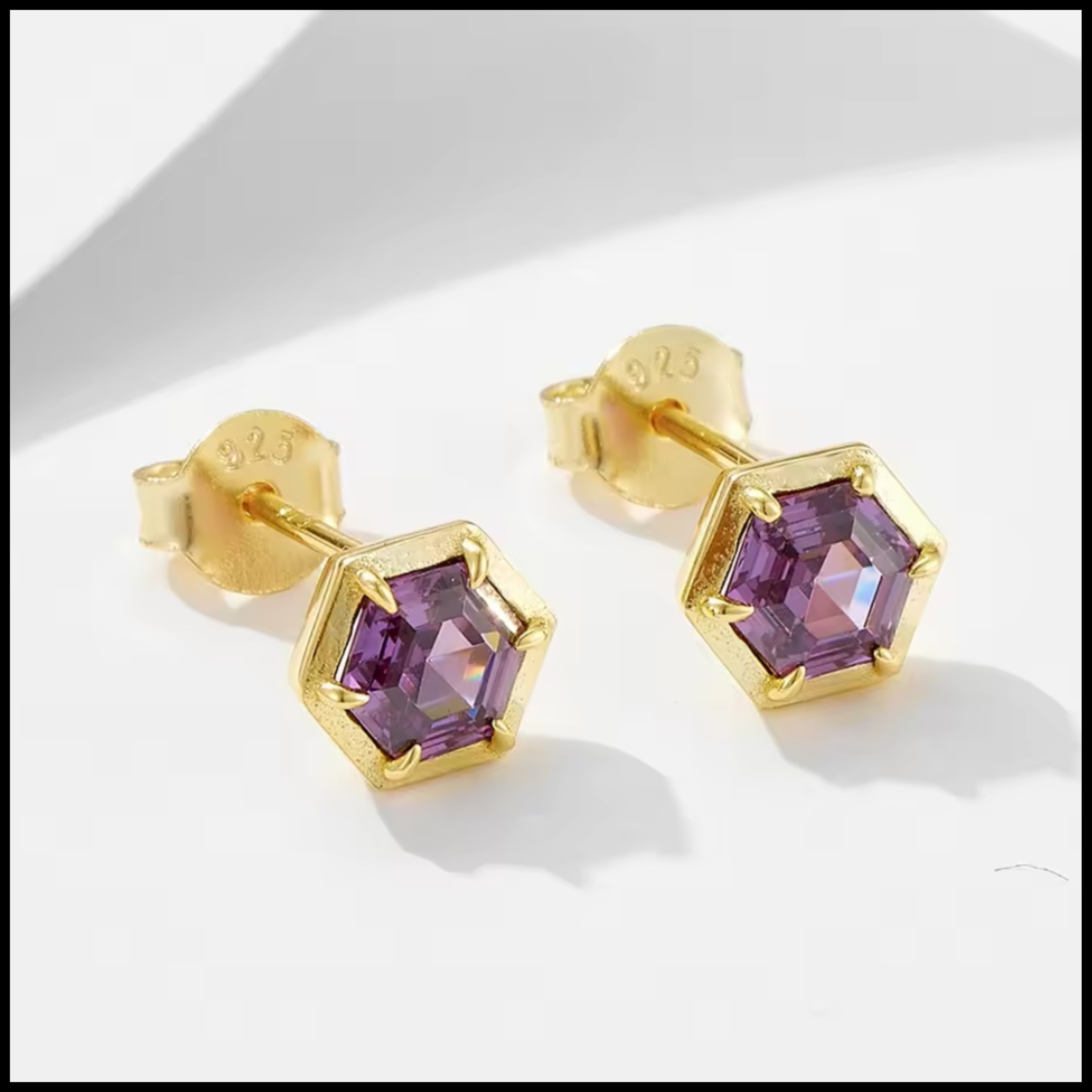 Gold earrings with purple gemstones on a white background