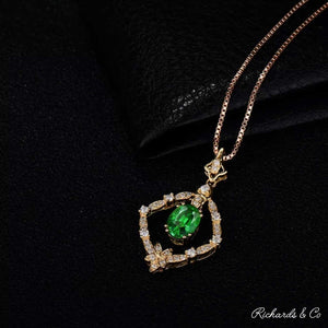 18K yellow gold Diamonds & Tsavorite pendant with oval green tsavorite and round white diamonds on chain against black background