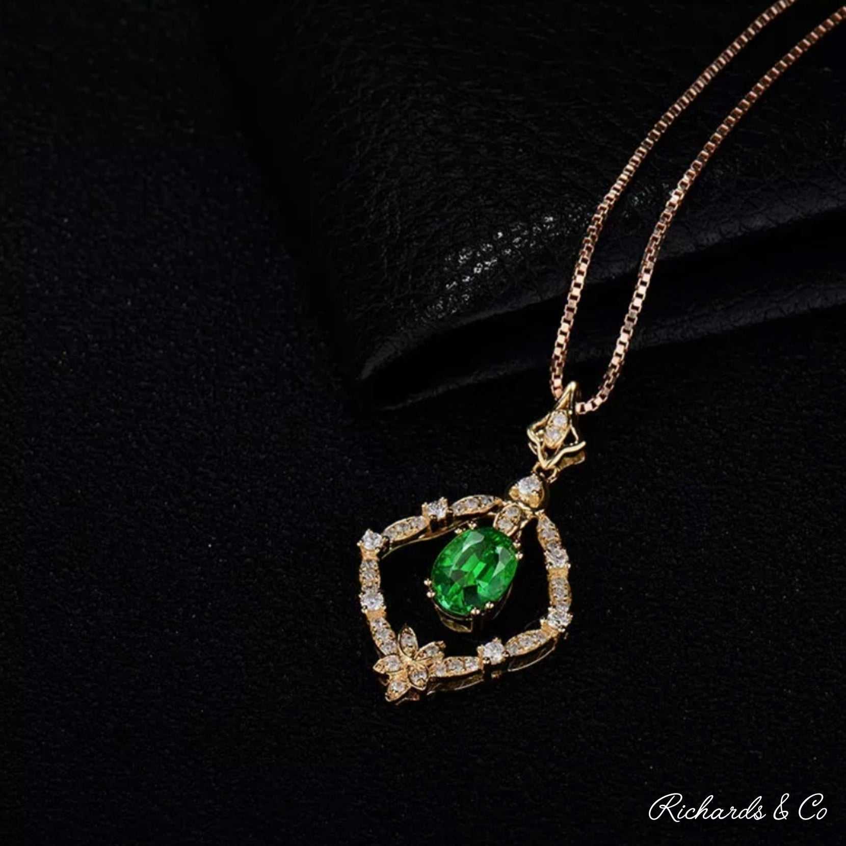 18K yellow gold Diamonds & Tsavorite pendant with oval green tsavorite and round white diamonds on chain against black background