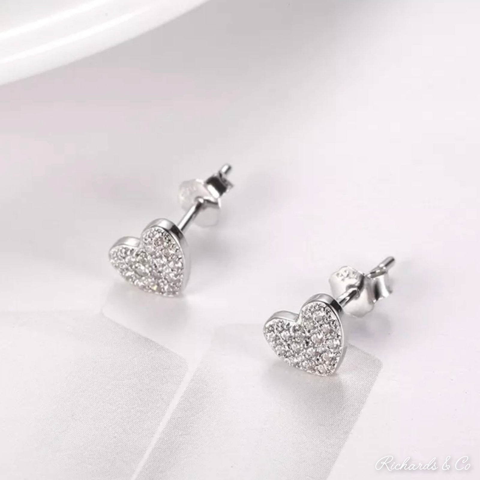 Pair of heart silver earrings with zirconia stones and stud design