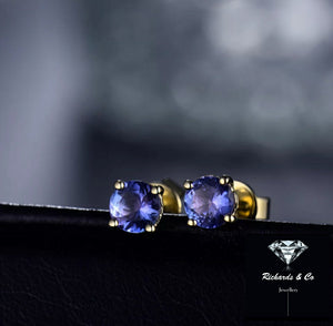 Close-up of natural tanzanite stud earrings set in 14K yellow gold with round 5mm violet-blue gemstones