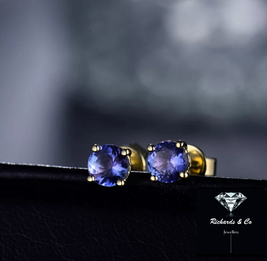 Close-up of natural tanzanite stud earrings set in 14K yellow gold with round 5mm violet-blue gemstones