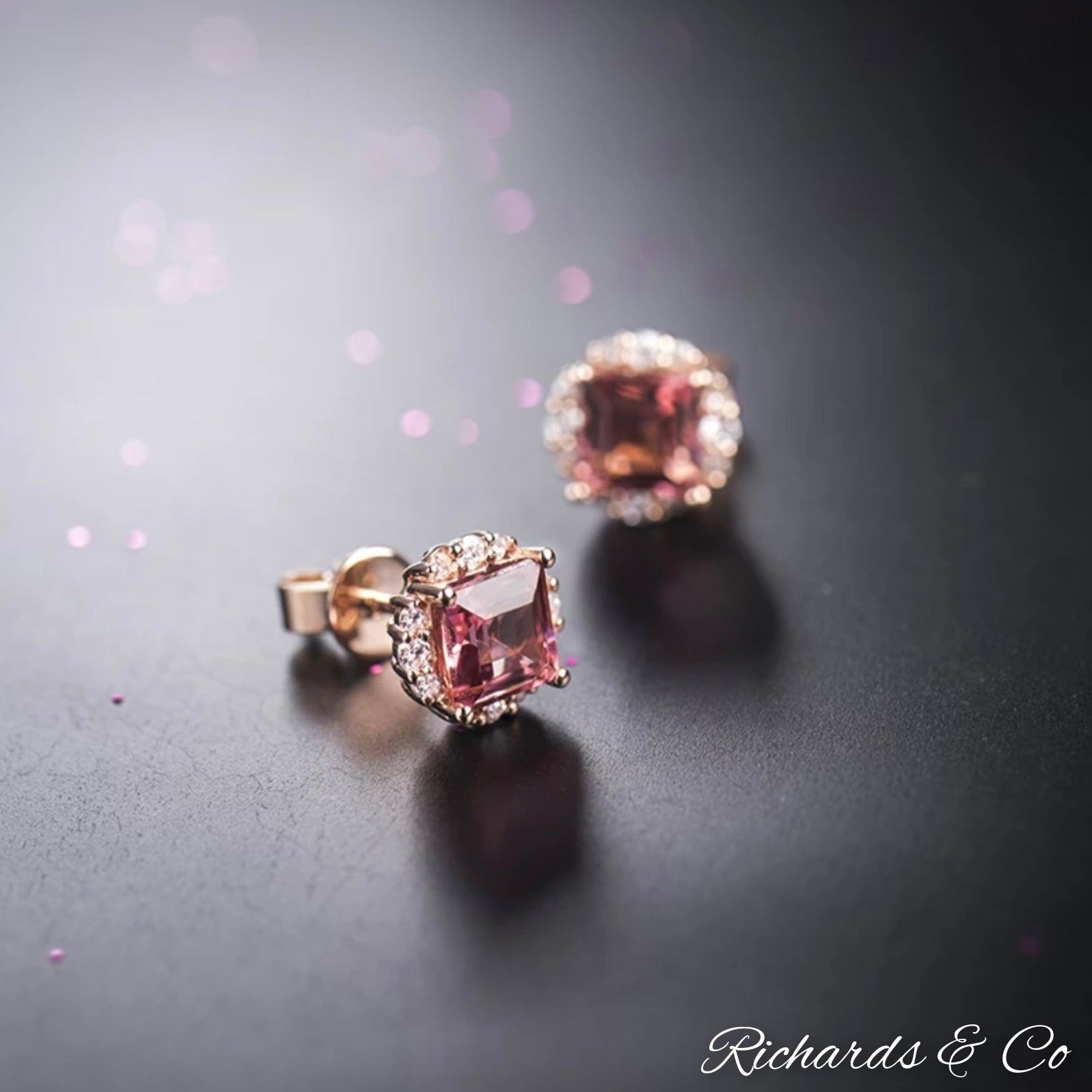 Close-up of natural pink tourmaline princess cut stud earrings set in 18K rose gold with diamond halo on dark background