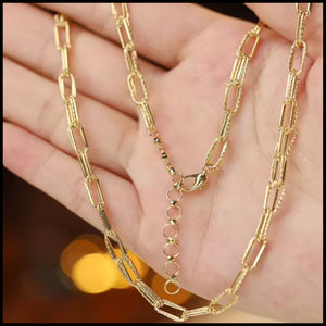 Gold chain necklace on a hand with a blurred background