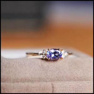 Blue Oval Stone Ring with gold-plated band and sparkling blue oval gemstone on soft fabric background