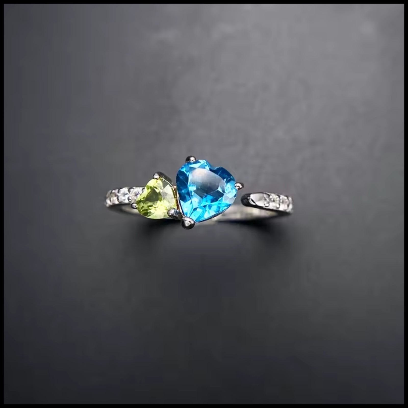 Ring with heart-shaped blue and green gemstones on a dark background