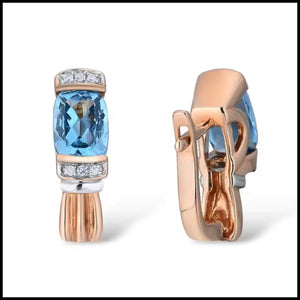 Rose gold earrings with blue gemstones and clear stones on a white background