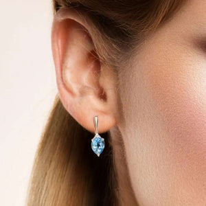 Close-up of woman's ear wearing Blue Topaz & Diamond yellow gold teardrop stud earring