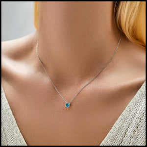 Necklace with a blue gemstone worn by a person