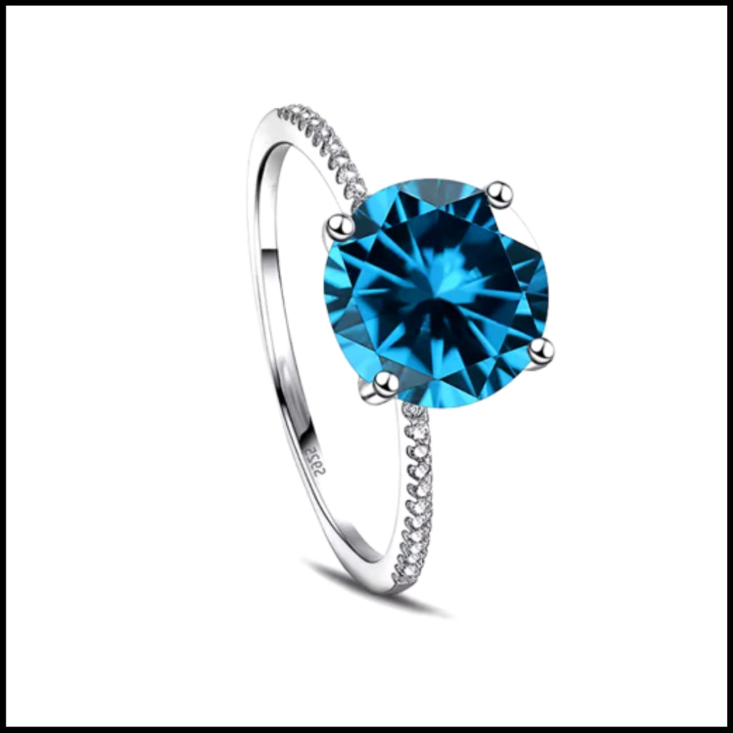 A solid silver ring with a large blue zirconia centerpiece and smaller stones around the band