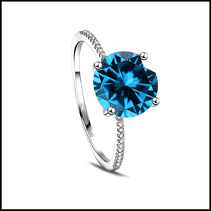 A solid silver ring with a large blue zirconia centerpiece and smaller stones around the band