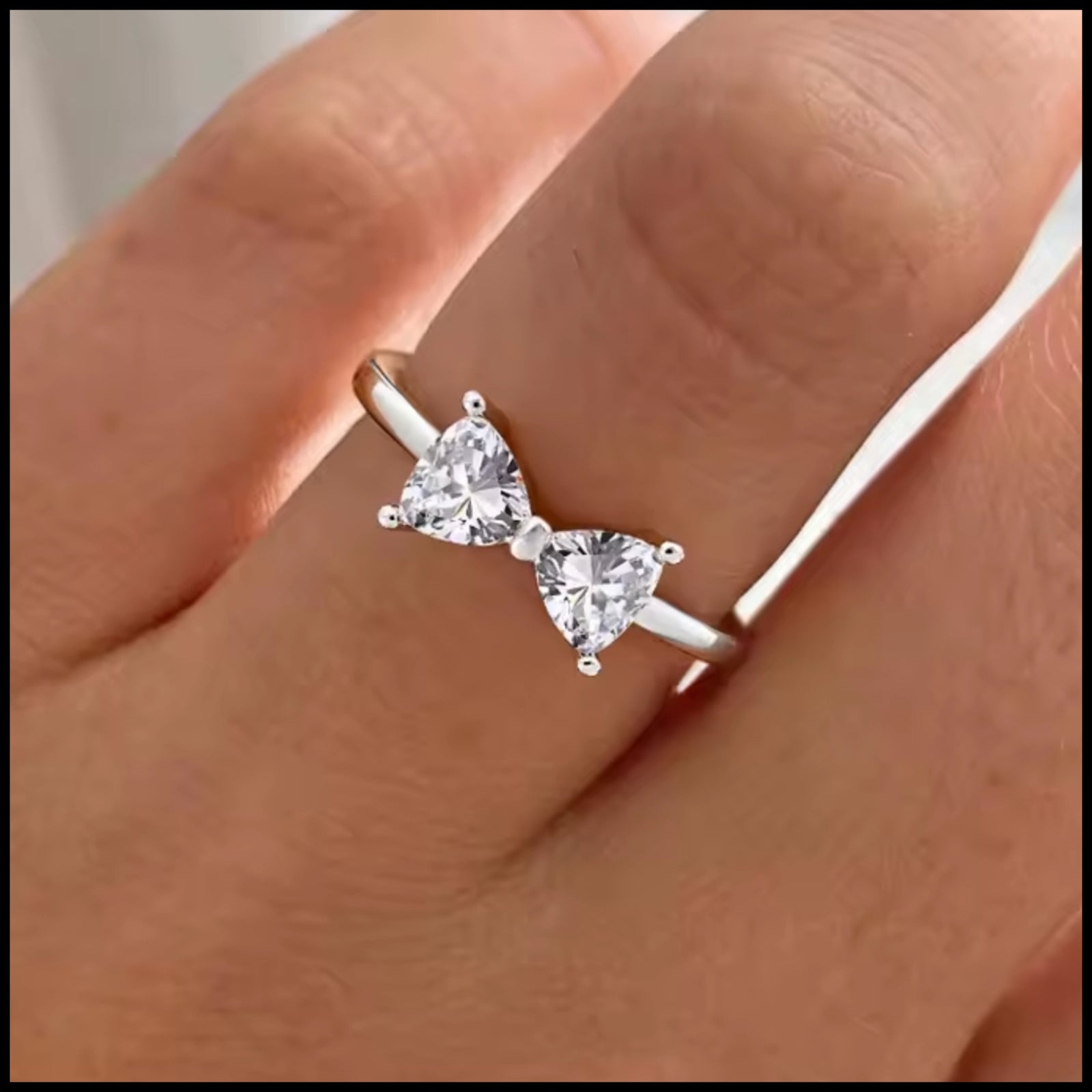 bow silver ring with sparkling heart-shaped stones on finger
