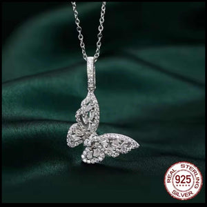 Silver butterfly pendant necklace on a dark green fabric background with 'Real Sterling Silver' 925 stamp.