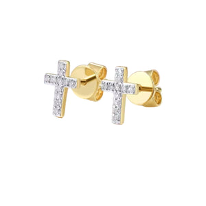 Gold cross earrings with clear stones on a white and pink background
