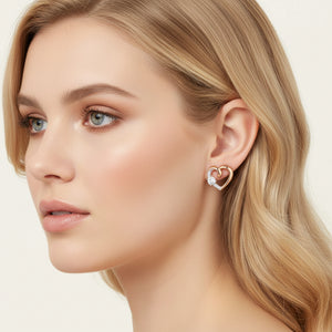 Rose gold heart-shaped earrings with clear gemstones on a light background