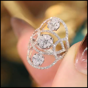 White gold ring with multiple diamonds held between fingers against a blurred background