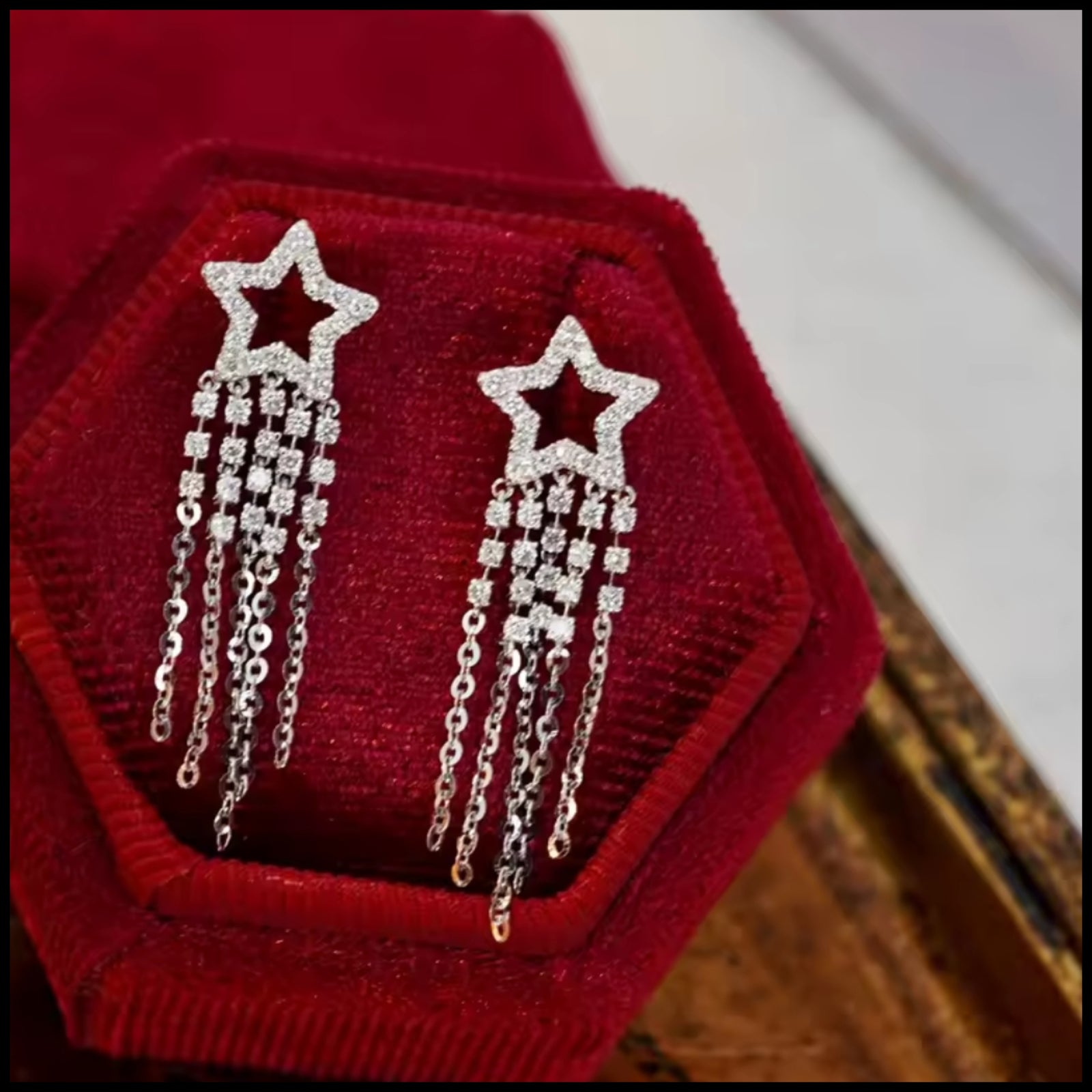 Star-shaped earrings with chains on a red fabric background