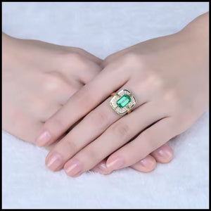 Hand wearing a ring with a green  emerald gemstone on a white background