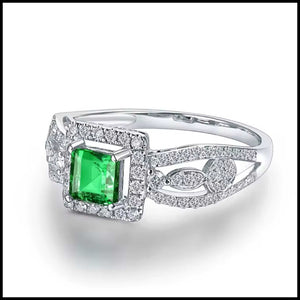 Diamond ring with a green emerald gemstone on a white background