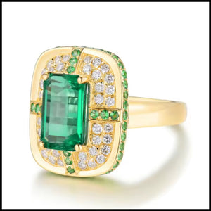 Gold ring with a large green emerald gemstone and smaller diamonds on a white background