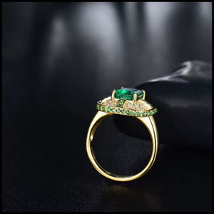 Gold ring with green gemstones on a dark background