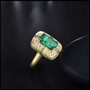 Gold ring with emerald and diamonds on a dark background