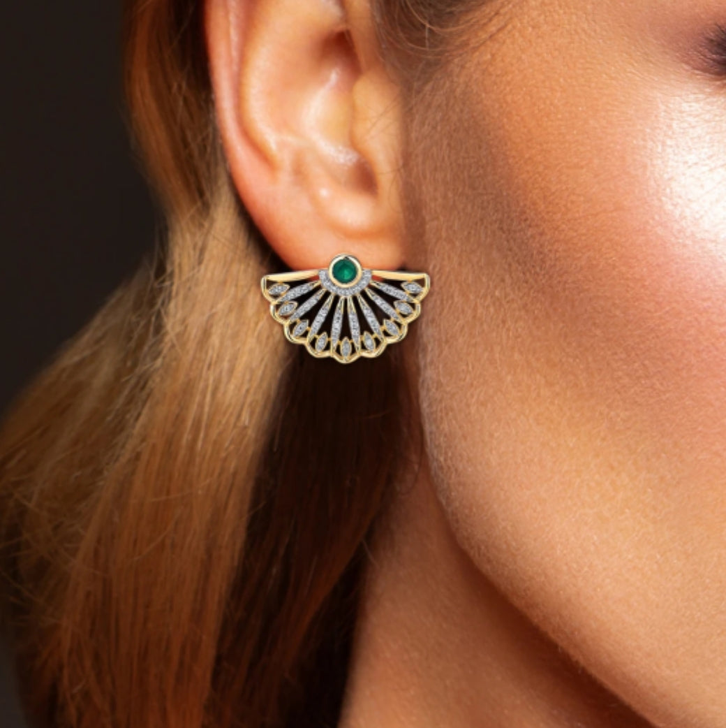 A person wearing a gold-colored emerald and diamond oriental fan design earring.