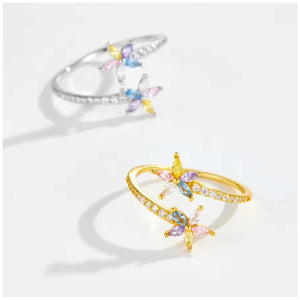 Two flower-shaped rings, one gold and one silver, on a white background.