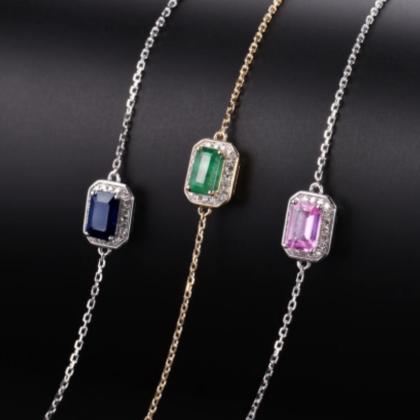 A series of three delicate bracelets with solid 14k gold bands. Each bracelet features a different combination of blue, pink, and emerald gemstones, set in an octagon cut design.
