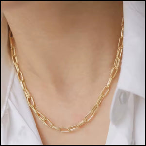 Gold chain necklace on a person wearing a white shirt