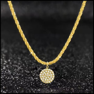 Gold necklace with a circular pendant on a black textured background