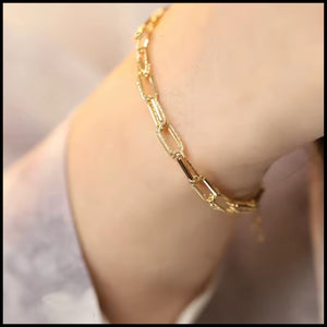 Gold chain bracelet on arm with a blurred background