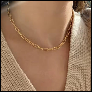 Gold chain necklace worn by a person in a beige sweater.
