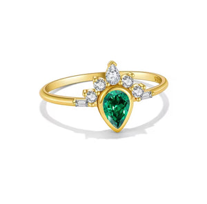 A yellow gold ring featuring a pear-cut green emerald center stone, surrounded by small round clear stones and baguette accents on a white background.