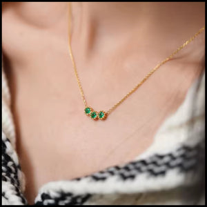 Gold necklace with green gemstones worn by a person
