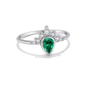A silver ring featuring a pear-cut green emerald colour center stone and a cluster of small clear stones above it, shown on a clean white background.
