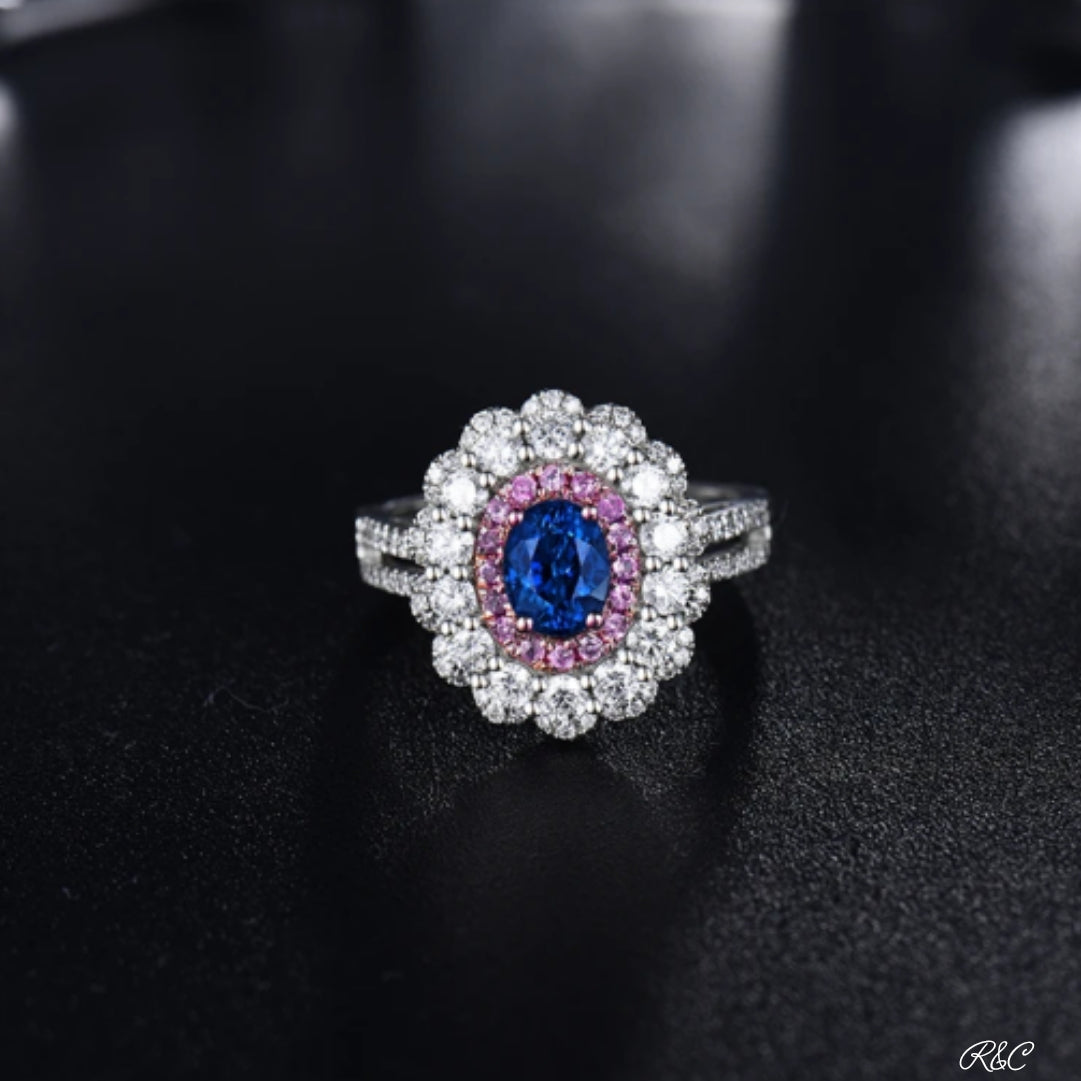 18K white gold ring with oval blue sapphire center, pink sapphires, and surrounding diamonds on black background