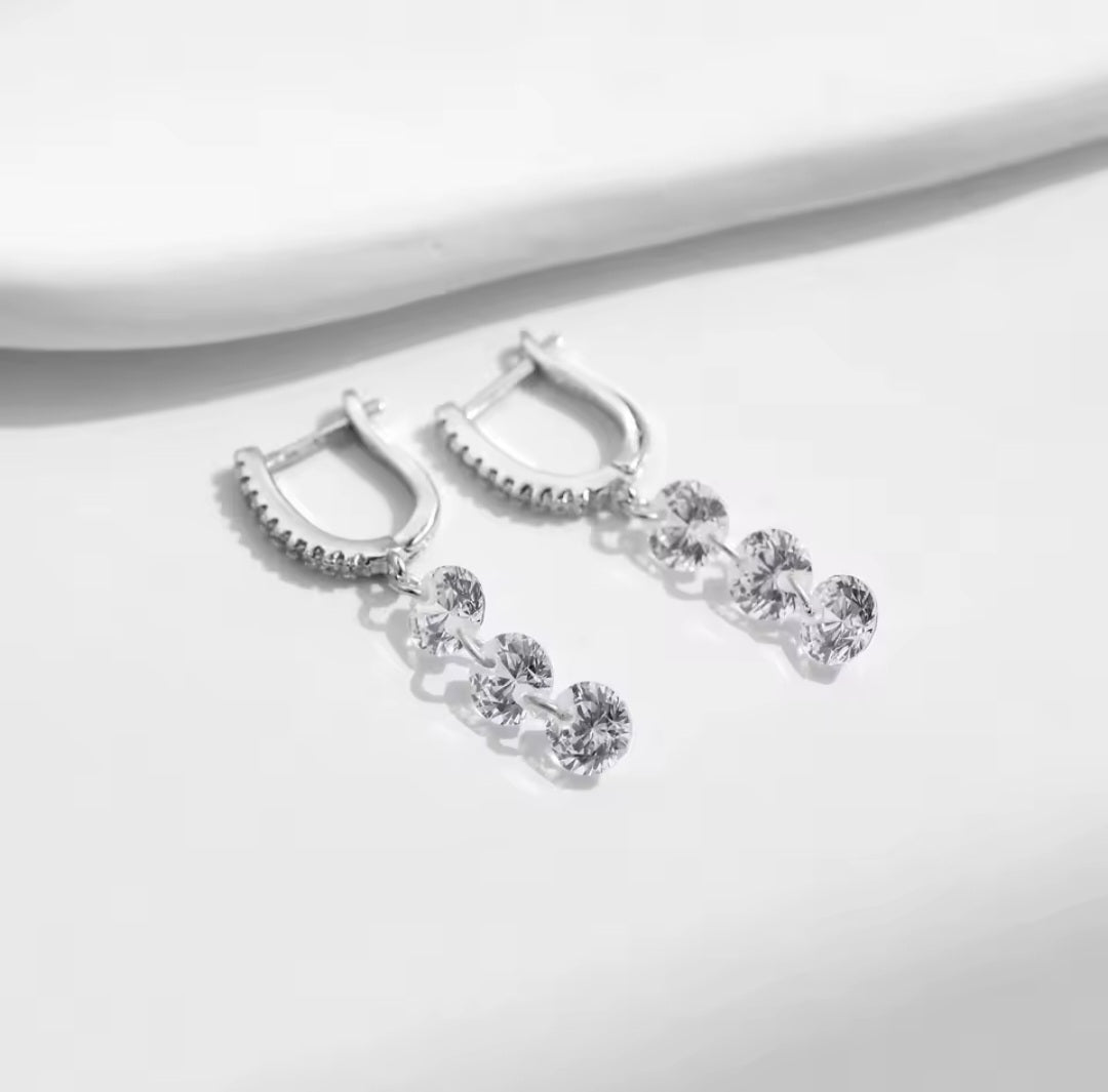 Silver earrings with clear gemstones on a white background