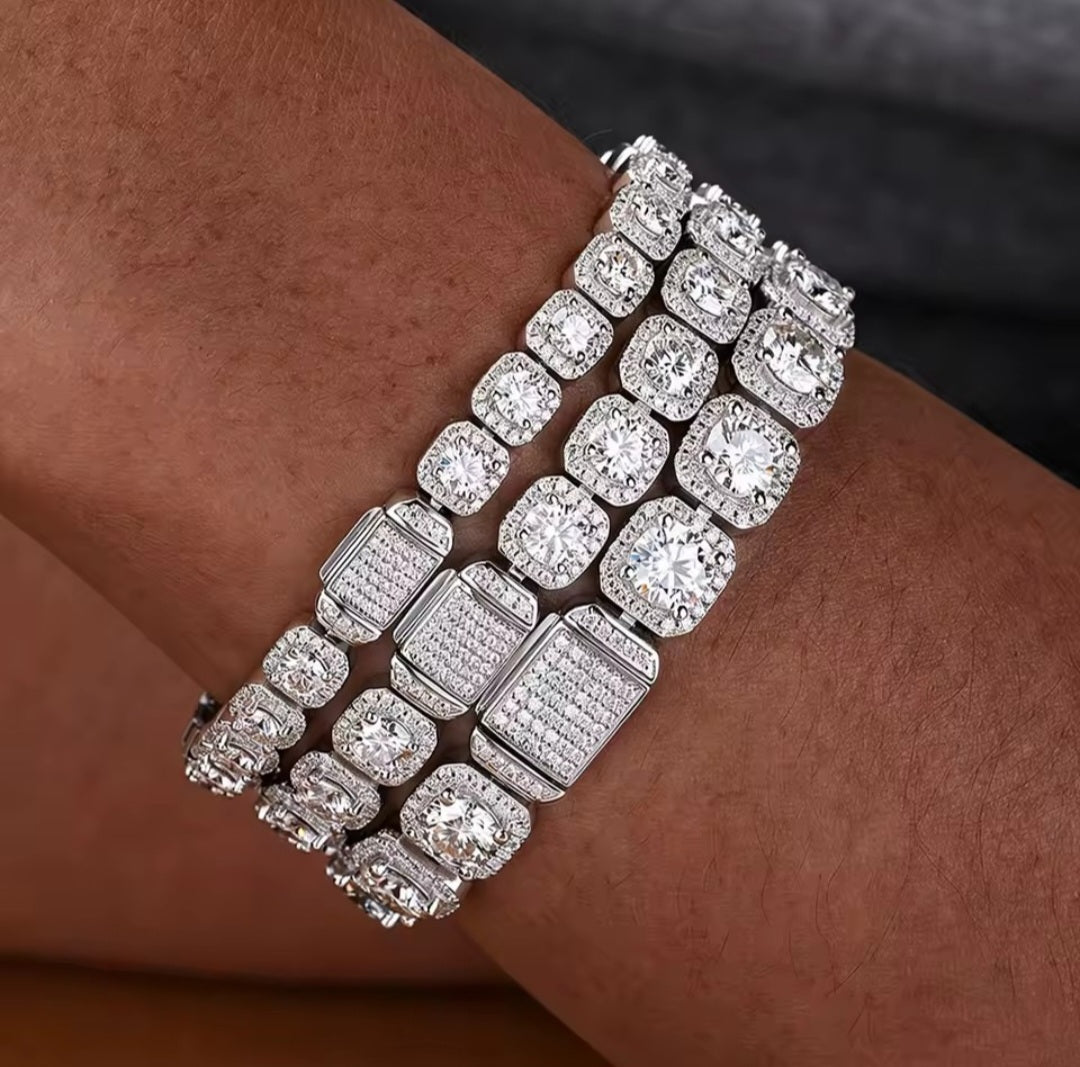 A close-up of a multi-strand bracelet worn on a wrist, featuring silver-toned metal with large cushion-cut and rectangular pavé-set clear stones.