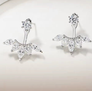 A pair of silver stud earrings with clear marquise and round-cut stones, arranged on a clean off-white background.