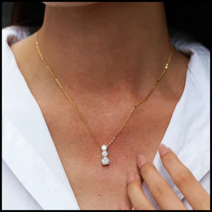 Three-stone moissanite necklace with triple-layer gold plating on solid silver, featuring a 6.5mm center stone and two side stones worn on a delicate gold chain