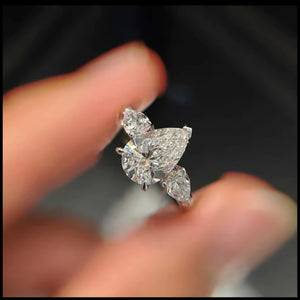 Diamond/ Moissanite ring held between fingers against a blurred background