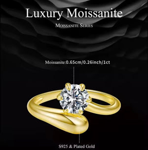 A luxury moissanite ring featuring a round brilliant-cut clear gemstone on a polished yellow gold band, set against a dark textured background with text detailing the stone size and gold purity.