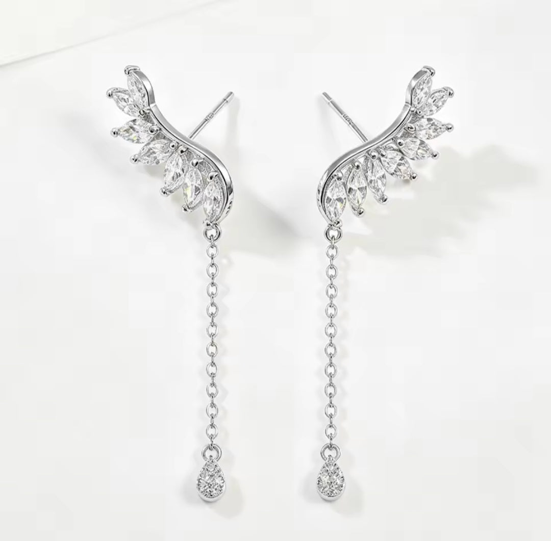 A pair of silver drop earrings with wing-like marquise-cut clear stones and dangling chain ends, shown on a clean white background.