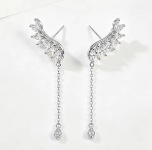 A pair of silver drop earrings with wing-like marquise-cut clear stones and dangling chain ends, shown on a clean white background.