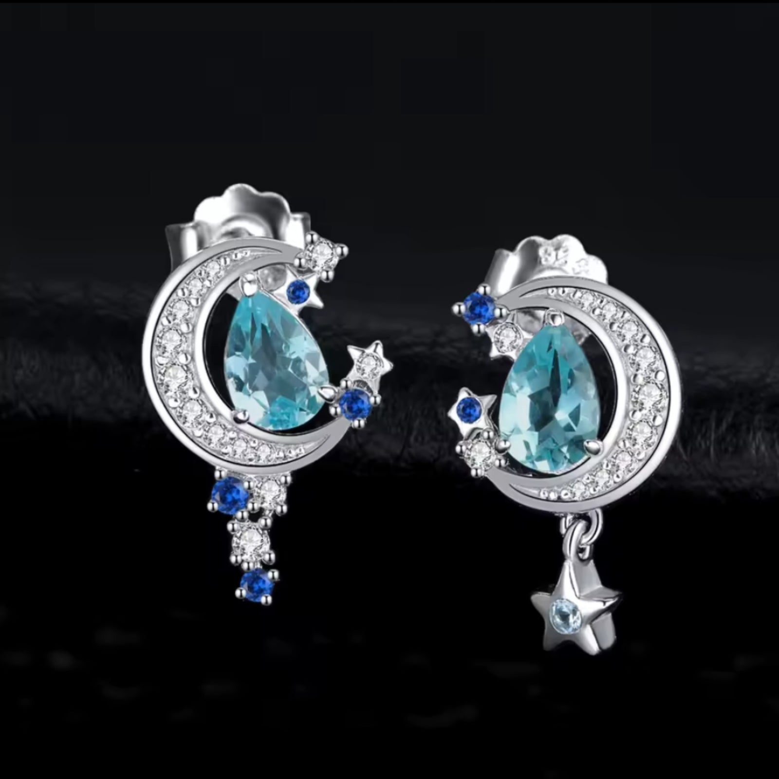 Silver earrings with blue gemstones on a dark background