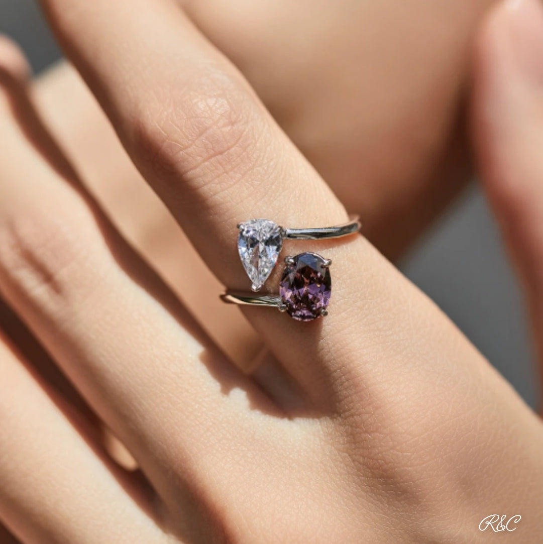 A close-up image of a woman's hand displaying a silver oval zirconia ring with a small, sparkling cubic zirconia embellishment on the finger.