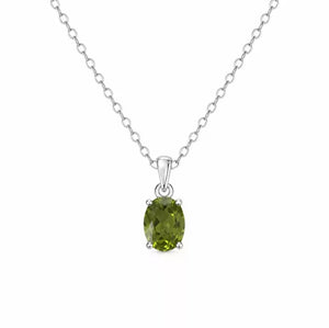 A silver chain necklace with an oval-cut green peridot gemstone pendant in a four-prong setting, shown against a plain white background.