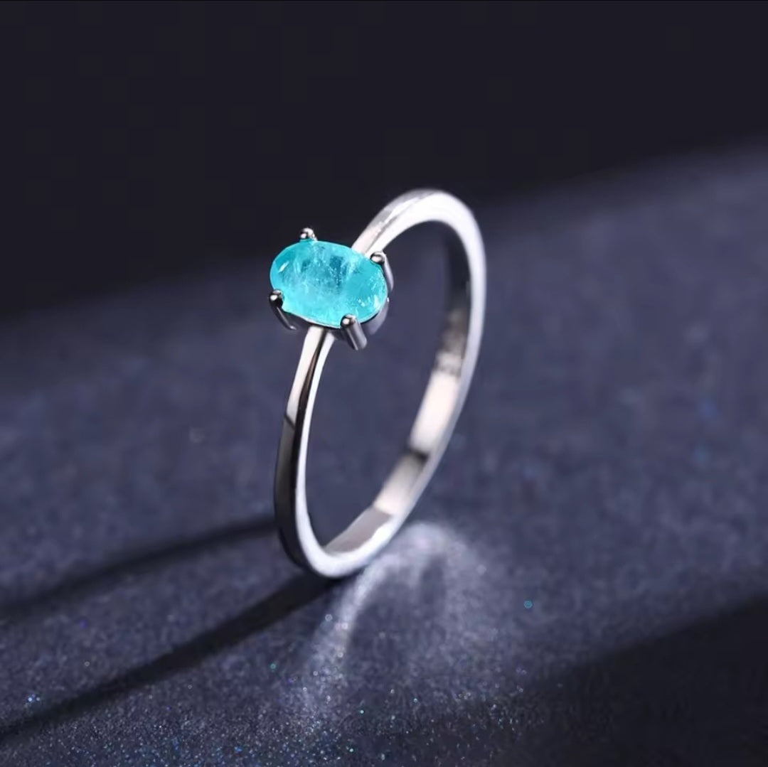 Silver ring with a blue gemstone on a dark background